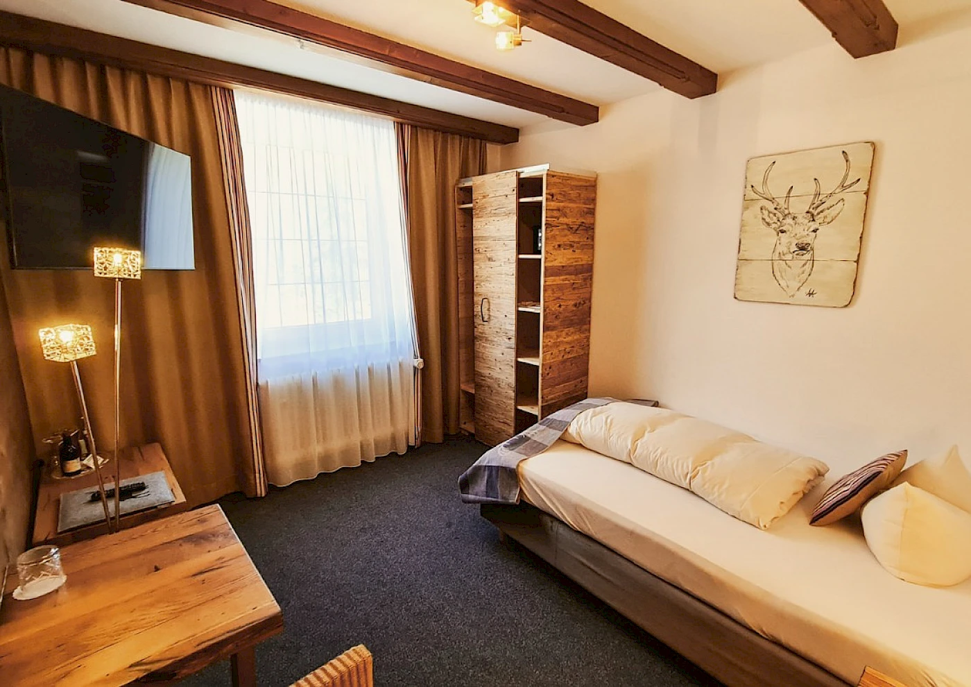 Overview of single room with bed, TV & colourful details