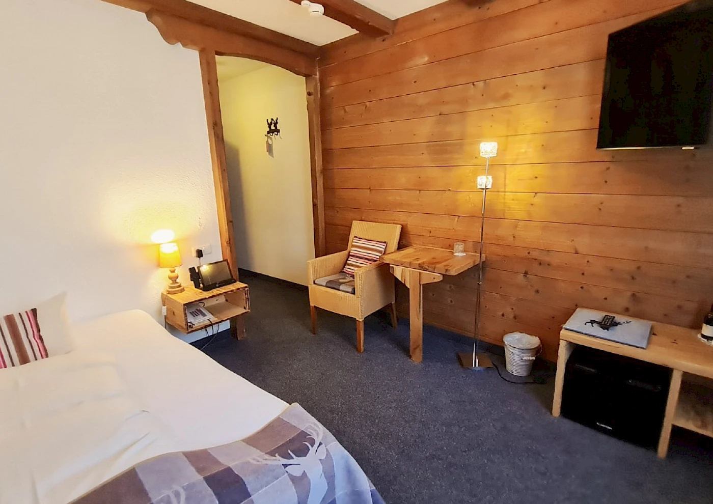 Overview of single room with bed, TV & colourful details